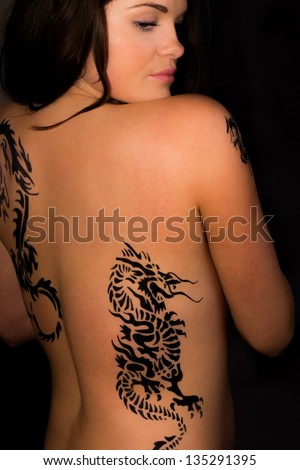 Sexy topless girl with tribal dragon tattoo on her back