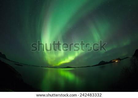 Aurora Borealis (Northern lights) Over coastal sea with reflection and fish-eye lens