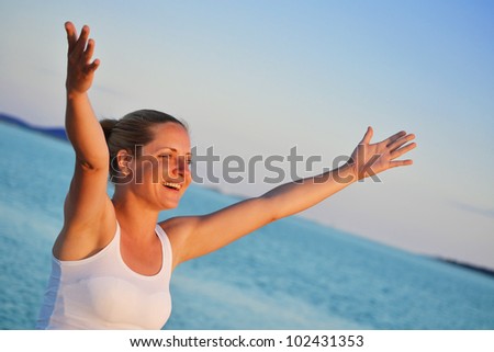 Young woman with hands up expressing joy on the beach