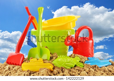 Plastic children toys for playing in sandpit or on a beach over the blue sky