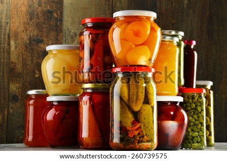 Jars with pickled vegetables, fruity compotes and jams in cellar. Preserved food