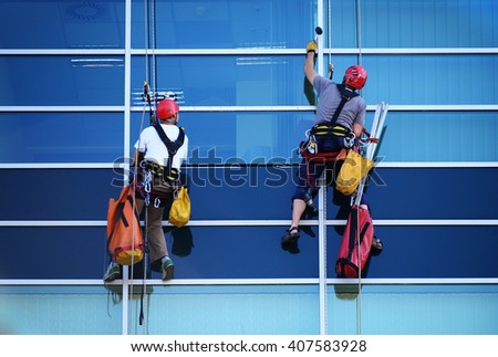 Two construction workers working at height on modern commercial skyscraper.