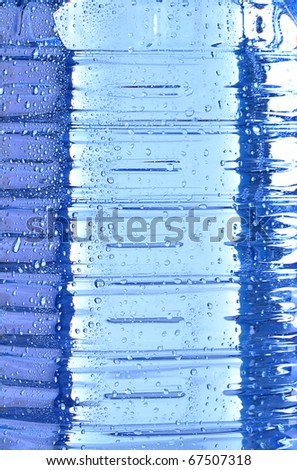 Texture of polycarbonate plastic bottle of mineral water with drops of water