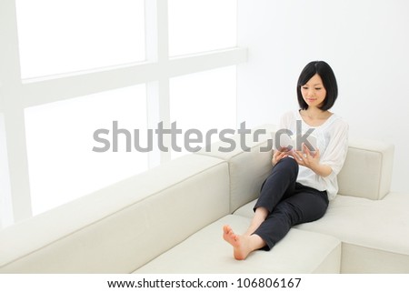 attractive asian woman relaxing and reading a book on the couch