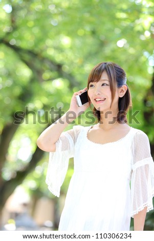 Portrait of beautiful young woman,speaking on mobile phone at summer green park.