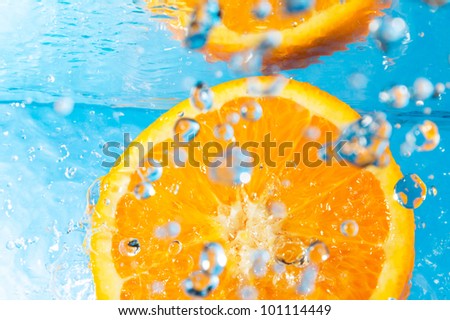 Orange splash in water, top view, bubbles with fruit reflection