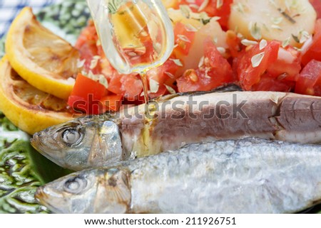 pouring olive oil in very fresh sardines cooked in sea salt - traditional food from Portugal