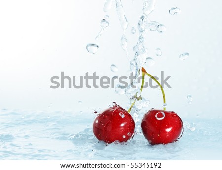 blurry water being poured on cherries isolated on light blue background