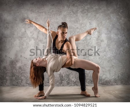 Two person, dancers, woman and man in dynamic action figure pose under light on the grunge background.