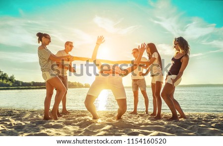 Happiness Friends funny game on the beach under sunset sunlight in summer sunny day.