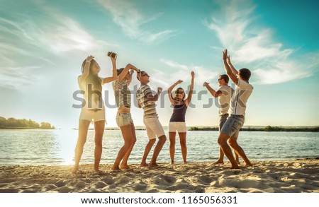 Happy Friends in funny dance on the beach under sunset sunlight in summer sunny day.