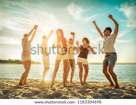 Happy Friends funny dance on the beach under sunset sunlight. Sunny day and friendship.