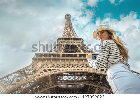 Woman tourist selfie near the Eiffel Tower in Paris under sunlight and blue sky. Famous popular touristic place in the world.