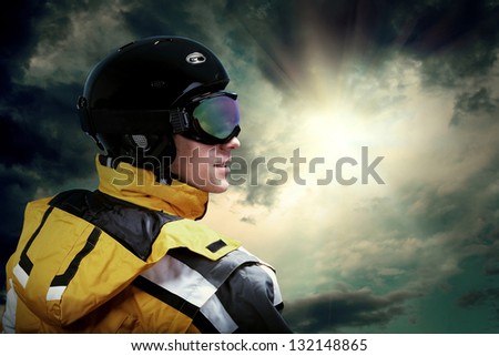 Portrait of man wearing a helmet and glasses on the background of sky with clouds