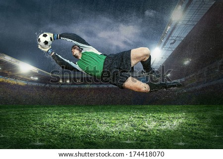 Football Golkeeper With Ball In Action Under Rain In Stadium