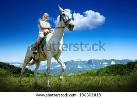 Young horsewoman riding on white horse, outdoors view