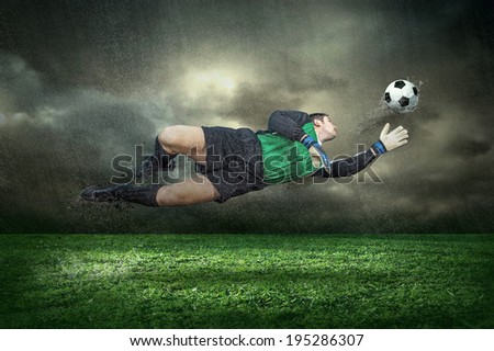 Football player with ball in action under rain outdoors