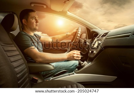 Man sitting and driving in the car under sunset sky