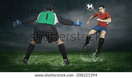 Two Football players in action under rain outdoors