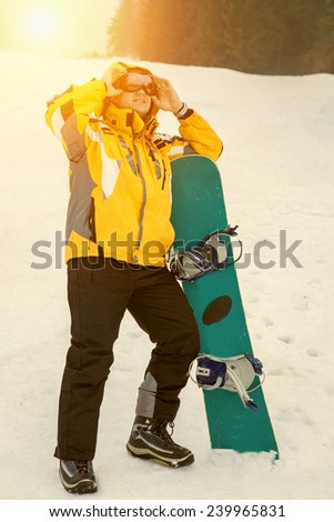 Men in goggles stay with snowboard