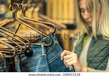 Beautiful blonde female looking jeans in the boutique
