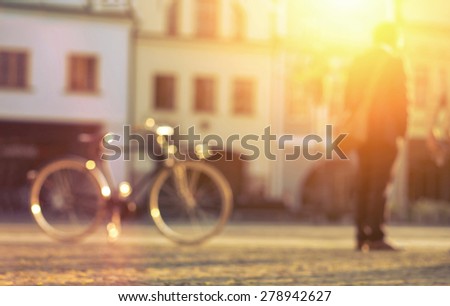 Blurred man with bicicle stay on the street at sunny day.