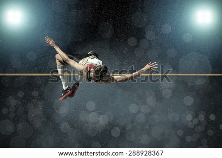Athlete in action of high jump under rain and bokeh background.