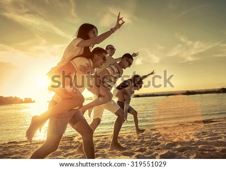 Friends fun on the beach under sunset sunlight.