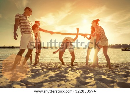 Friends funny game on the beach under sunset sunlight.