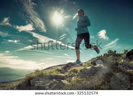 Female running in mountains under sunlight.