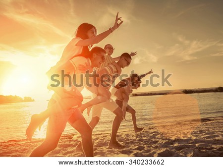 Friends fun on the beach under sunset sunlight.