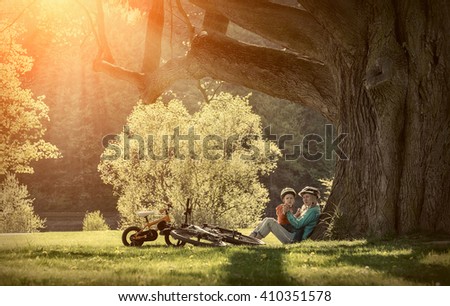 Mother and son with them bicycles in the park under sunlight.