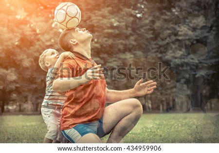 Father and son playing football in park at sunny day