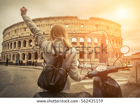Woman tourist near the Coliseum in Rome under sunlight and blue sky. Famous popular touristic place in the world.