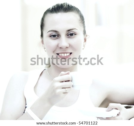 Happy woman in white with cup of coffee or tea at bedroom