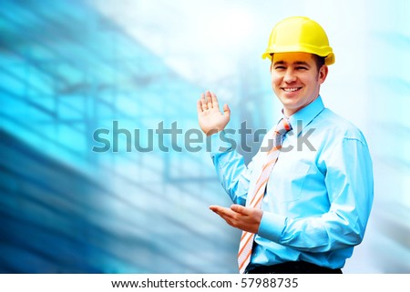 Young architect wearing a protective helmet standing on the building background