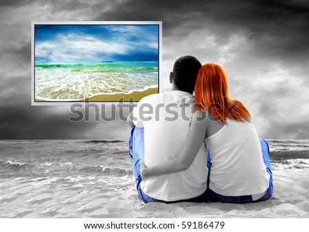Sea view of a couple sitting on beach and see TV monitor
