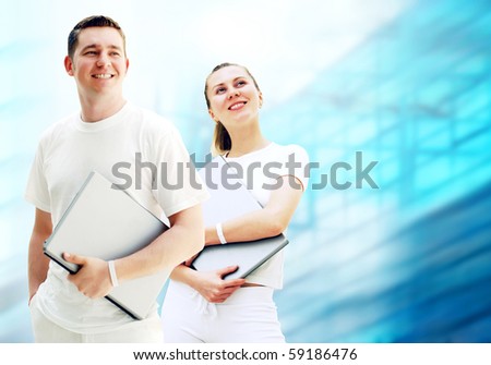 Pair of two happy young people or student with laptops on the business background