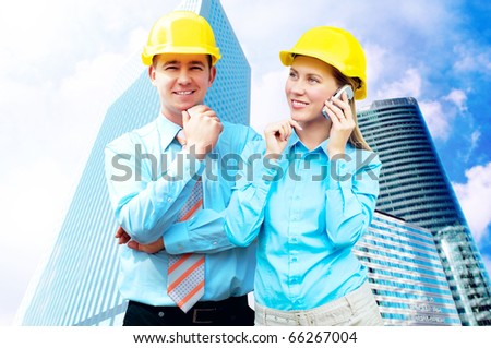 Young architects wearing a protective helmet standing on the building background
