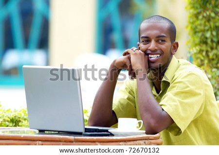 Young happy man or student with laptop sitting at the table
