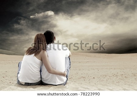 Young couple seating in desert in sunny day