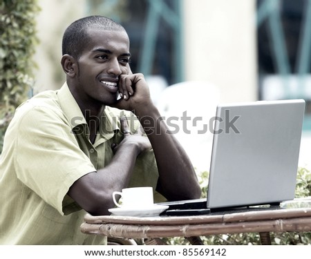 Young happy man or student with laptop sitting at the table