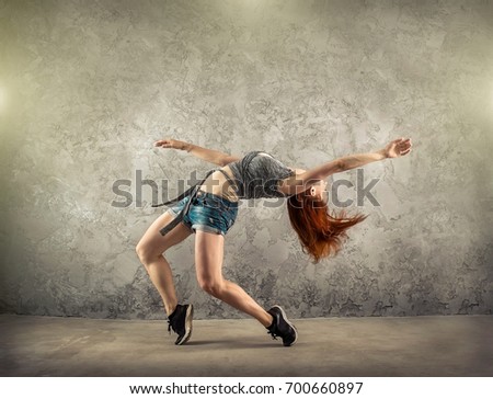 Woman dancer in dynamic action on the grunge grey background.
