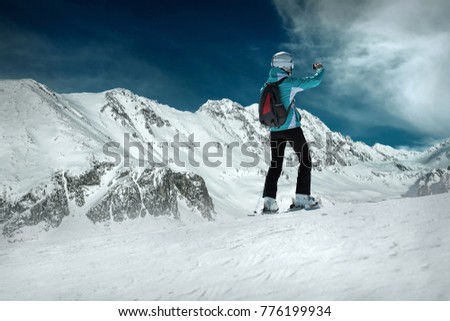 Woman stay on the ski and shoot selfie before sport action at sunny day around mountains under blue sky.