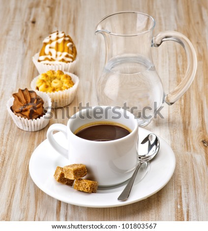 coffee, sugar, water and cakes on wooden board textured