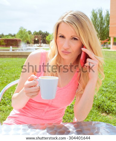 young woman drinking coffee and talking on the phone in a bar table