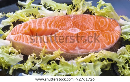raw salmon wheels black tray, with the leaves of salad