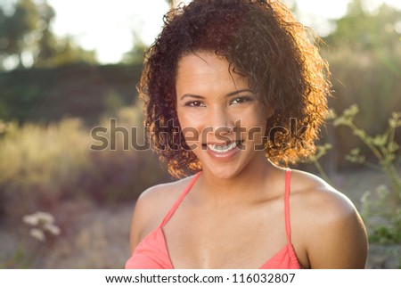 Smiling young beauty - Happy African American beauty with natural hair style in a field of tall grass, backlit by the sun