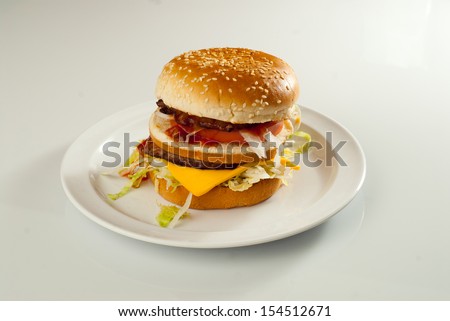 Double cheese burger - Tasty double cheese burger with lettuce and tomato on a plate. White background.