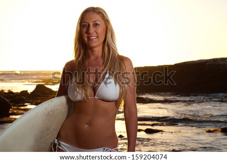Fit surfer girl - Attractive adult caucasian woman in white bikini with long blonde hair holding her surfboard